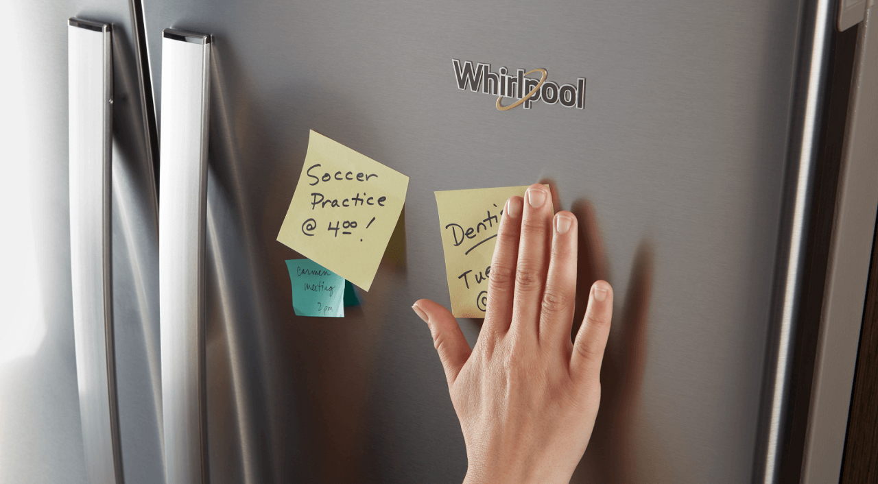 A person putting sticky notes on a WhirlpoolÂ® fridge