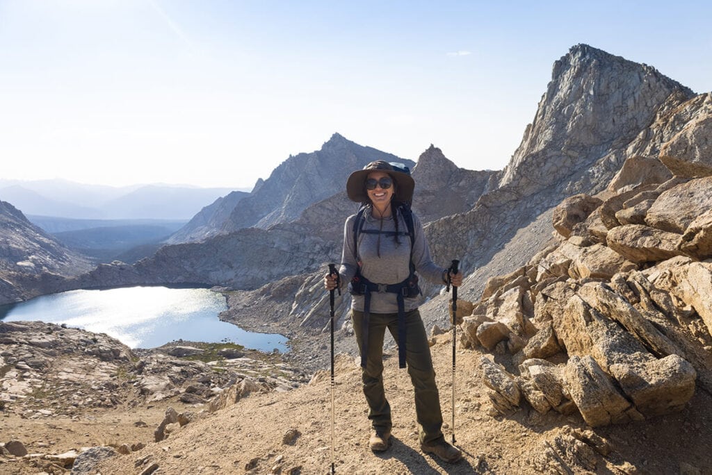 Female backpacker standing on trail in front of alpine lake on backpacking trip in Sequoia National park