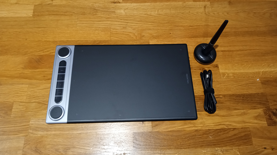 Huion Inspiroy Dial 2 review; a drawing tablet on a wooden table.