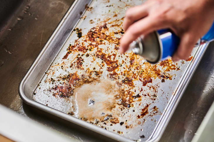 spraying easy off oven cleaner on a dirty baking sheet